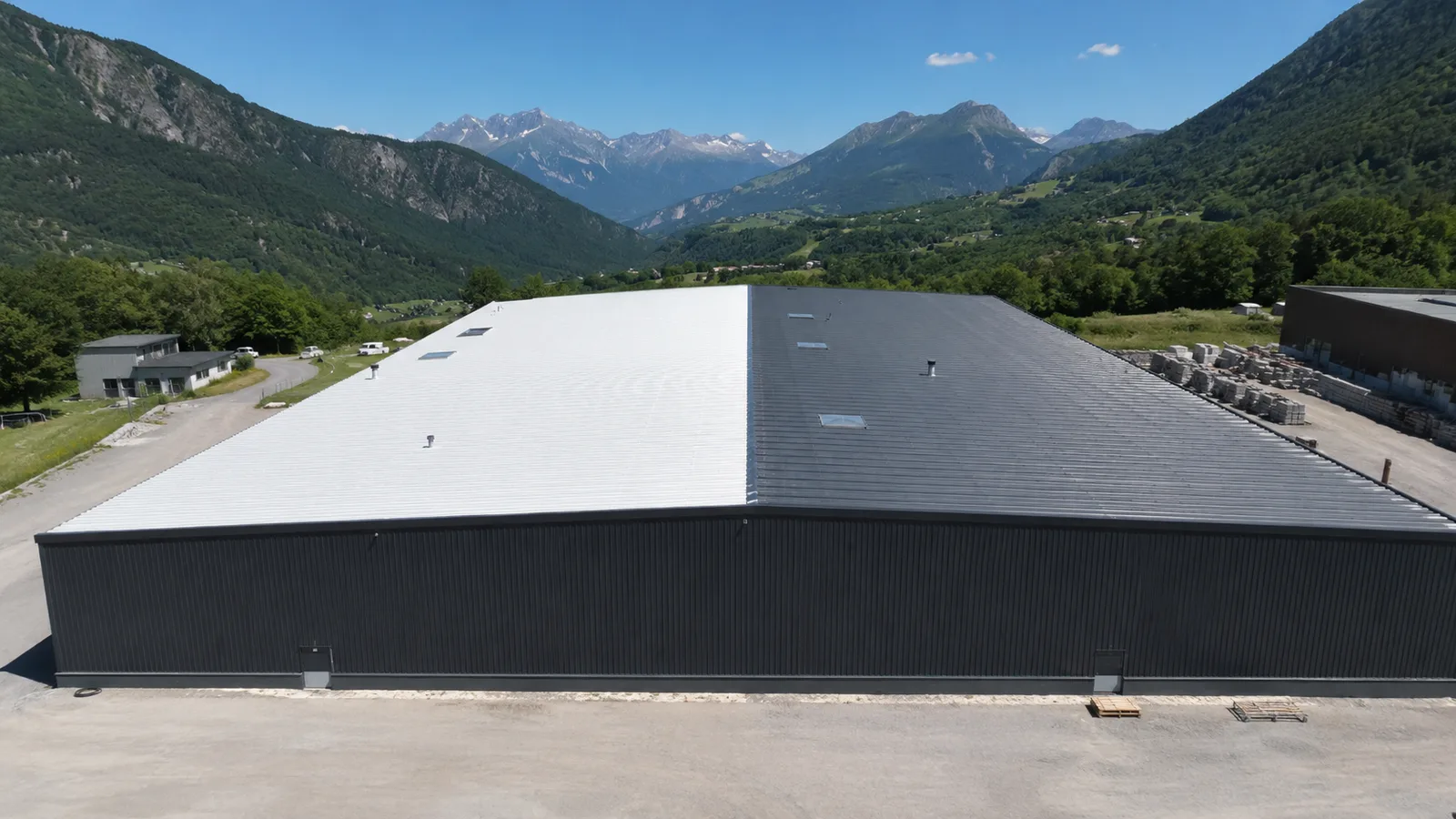 Toiture de bâtiment industriel en Haute-Savoie, moitié peinte en blanc réfléchissant, moitié en bac acier sombre